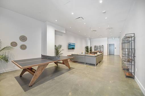 A room with a ping pong table in the middle.