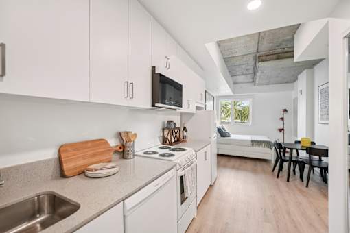 A kitchen with white cabinets and a wooden cutting board on the counter.