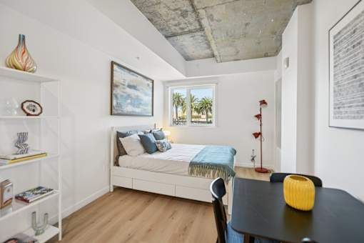 A bedroom with a bed, a table, and a chair.