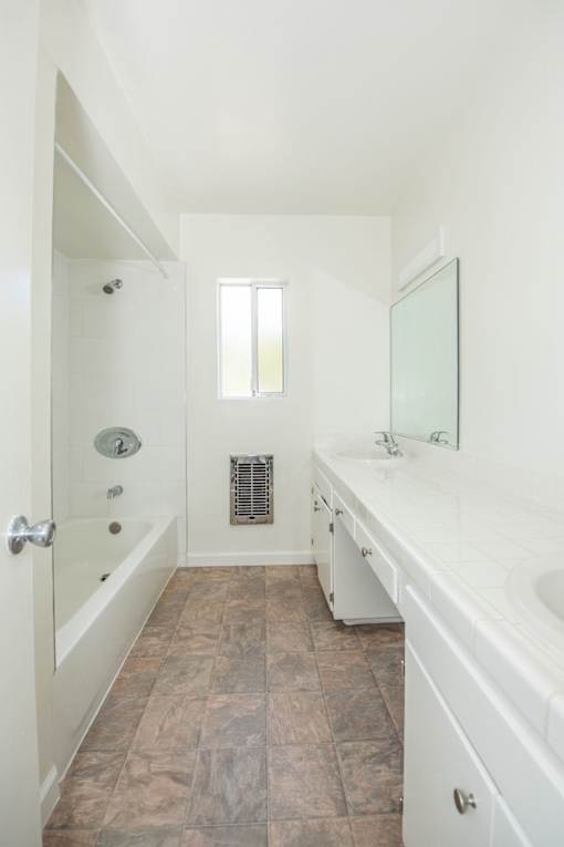 A white bathroom with a tiled floor and a window.