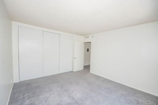 A room with white walls and a grey carpet.