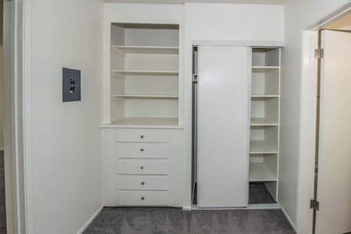 A white closet with drawers and shelves is open.