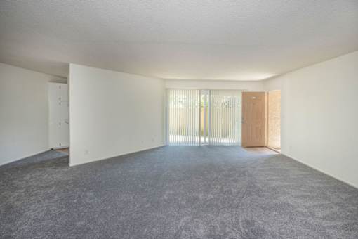 A room with a carpeted floor and a door on the right side.