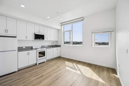 A kitchen with white cabinets and a vinyl floor.