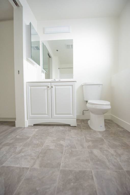 A white toilet sits next to a white cabinet in a bathroom.