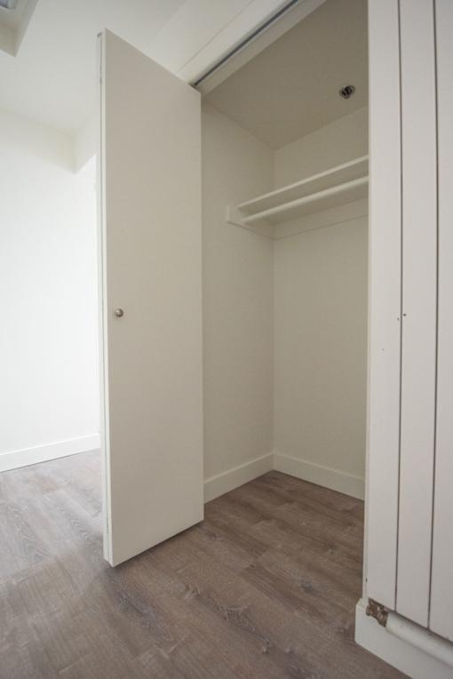 A white door is open to a room with a wooden floor.
