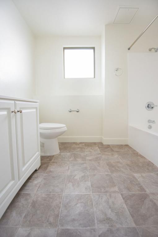 A bathroom with a toilet, sink, and tiled floor.