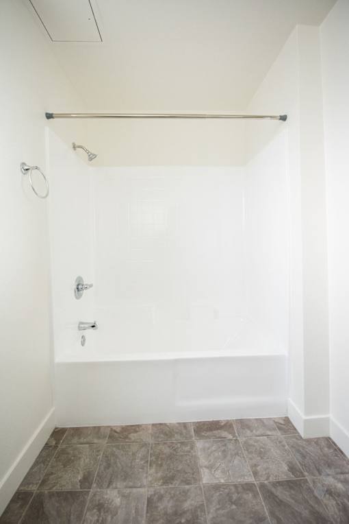 A white bathroom with a tiled floor and a shower.