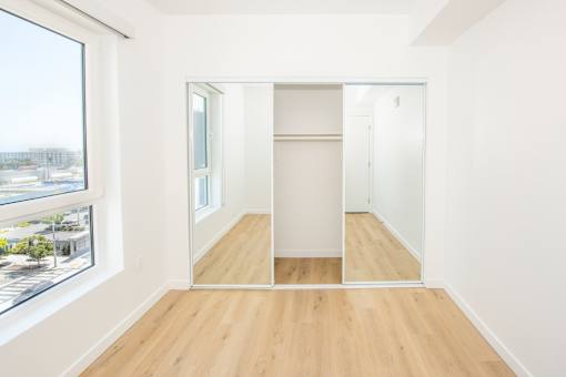 A room with a large mirror on the wall and a wooden floor.