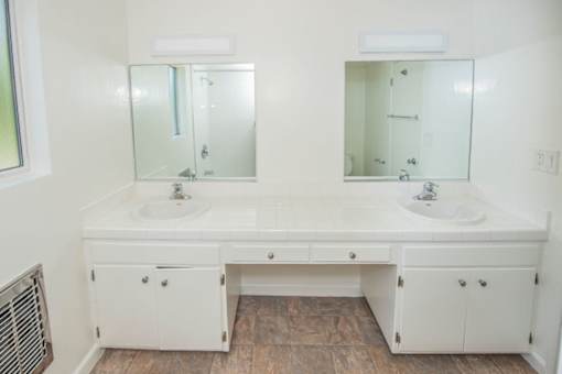 A white bathroom vanity with two sinks and two mirrors.