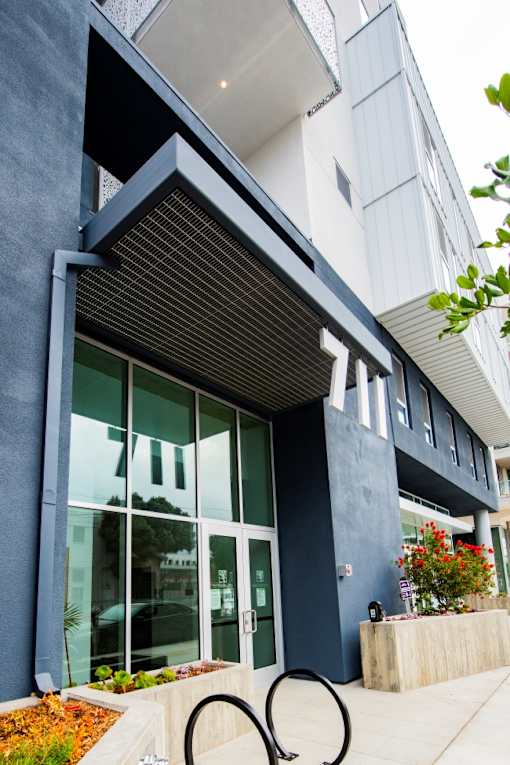 A modern building with a glass door and a black awning.