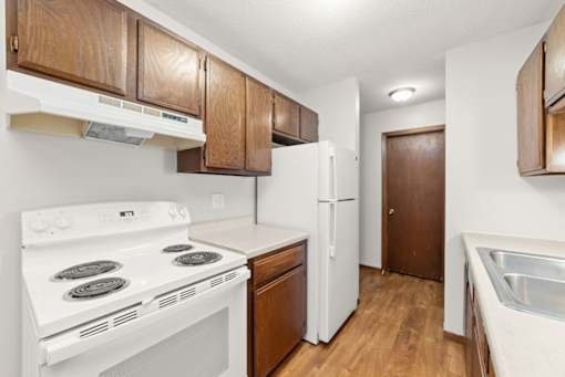 A kitchen with white appliances and wooden cabinets.