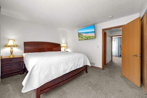 A bedroom with a large bed, two lamps, and a television displaying a landscape.