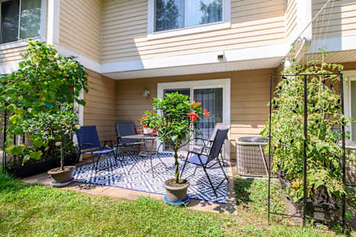 A patio with a table and chairs surrounded by plants.
