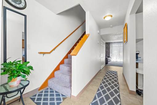 A hallway with a staircase and a plant on a table.