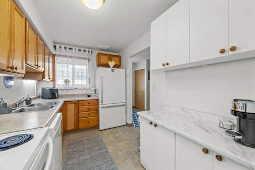 A kitchen with white cabinets and a white fridge.
