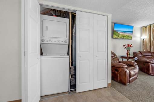 A white door is open to reveal a white oven and microwave.