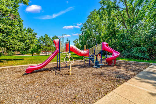 A playground with a red slide and a blue sky.