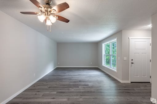 A room with a ceiling fan and a door.