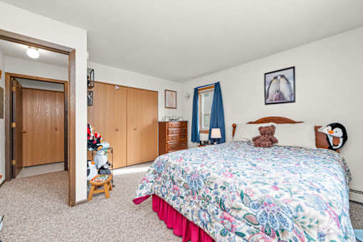 A bedroom with a floral bedspread and a teddy bear on the bed.