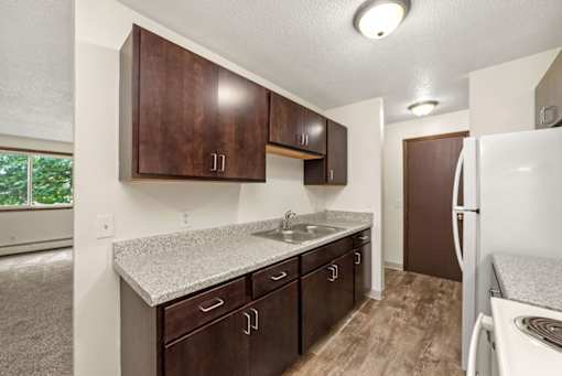 A kitchen with brown cabinets and a white fridge.