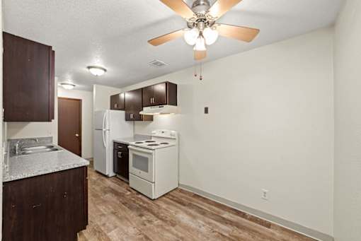 A kitchen with a refrigerator, oven, and stove.