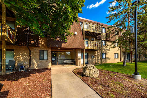 A large rock sits in the middle of a grassy area in front of a building.