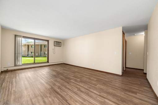 A room with wooden flooring and a sliding glass door leading to a balcony.