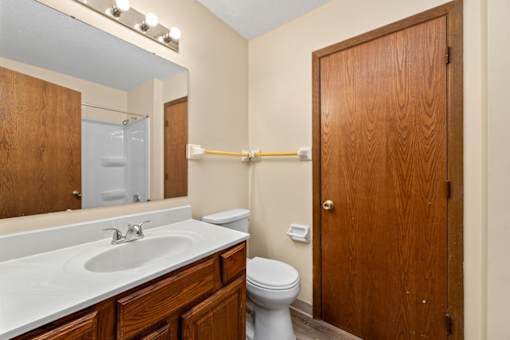 A bathroom with a toilet, sink, and mirror.