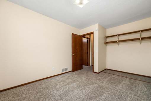 A room with a carpeted floor and a wooden door.