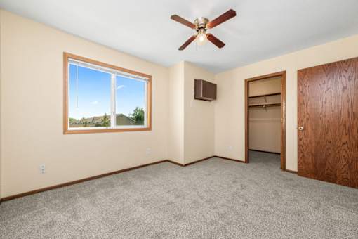 A room with a ceiling fan and a window overlooking a landscape.