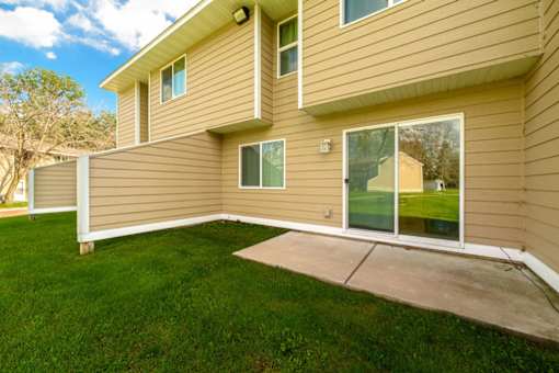A house with a tan siding and a green lawn.