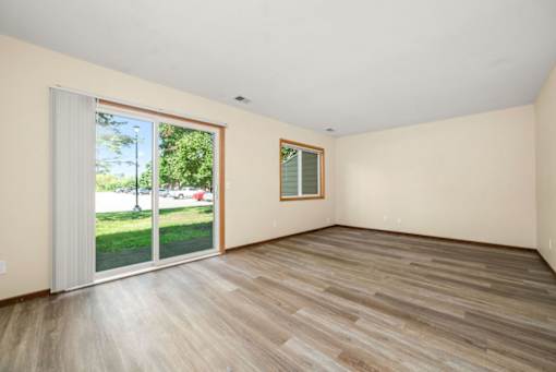 A room with wooden flooring and a sliding glass door leading to a green outdoor area.