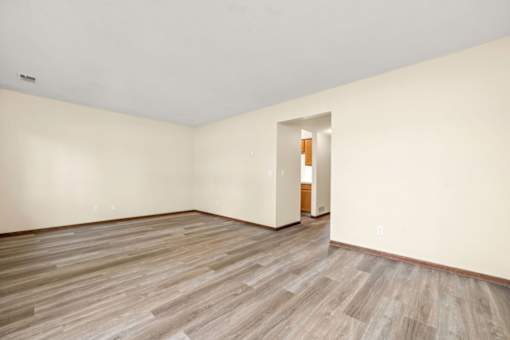 A room with wooden flooring and a doorway leading to another room.