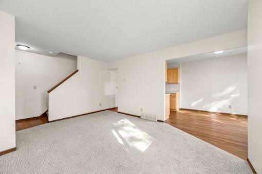 A large, empty room with a carpeted floor and a staircase.