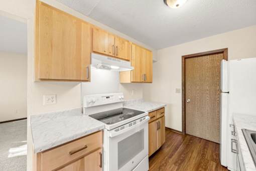 A kitchen with white appliances and wooden cabinets.