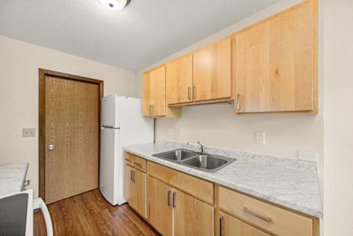 A kitchen with wooden cabinets and a white fridge.