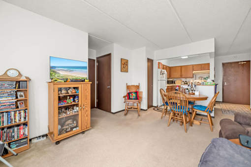 A living room with a television, a bookshelf, and a dining area.