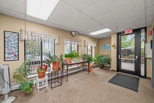 A room with a carpeted floor, a white ceiling, and a black door with an exit sign above it.