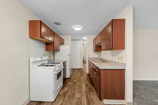A kitchen with white appliances and wooden cabinets.