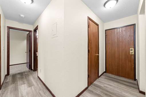 A hallway with two doors and a mirror on the wall.
