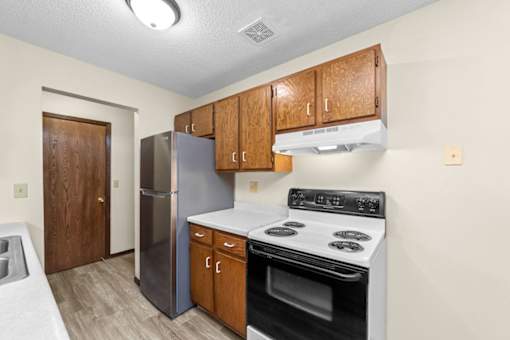 A kitchen with a stove, refrigerator, and cabinets.