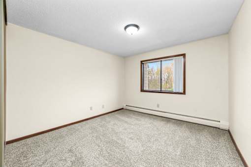 A room with a window and carpeted floor.