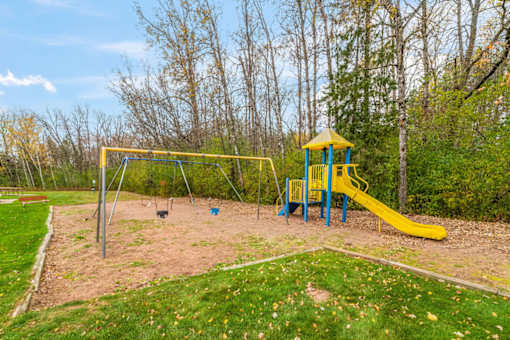 A playground with a yellow slide and a blue and yellow tower.