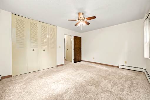 A room with a ceiling fan and carpeted floor.