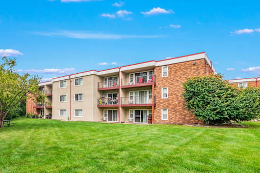 A red brick apartment building with a green lawn in front.