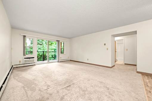A large empty room with a carpeted floor and a door leading to another room.