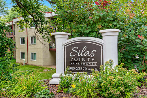 A sign for Dilla's Pointe Apartments stands in front of a building.