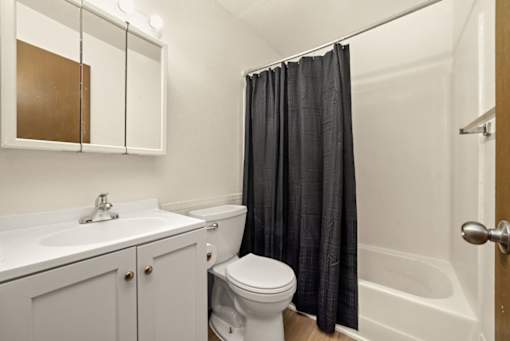 A white bathroom with a toilet, sink, and shower.