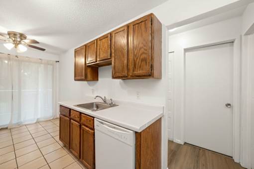 A kitchen with white countertops and wooden cabinets.